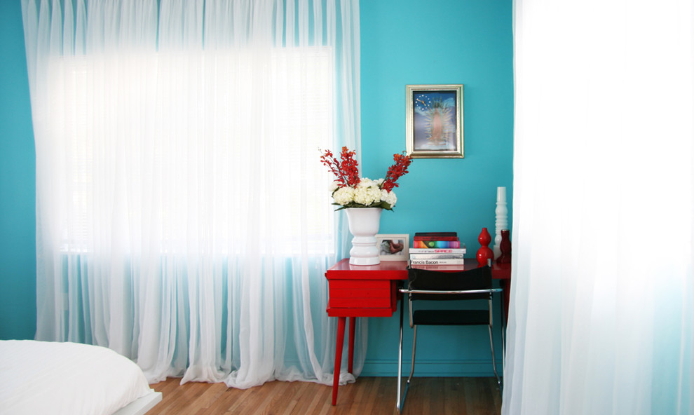 Cette photo montre une chambre tendance avec un mur bleu et un sol en bois brun.
