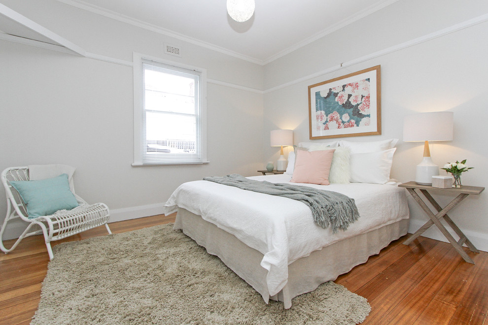 Ejemplo de dormitorio actual con paredes grises y suelo de madera en tonos medios