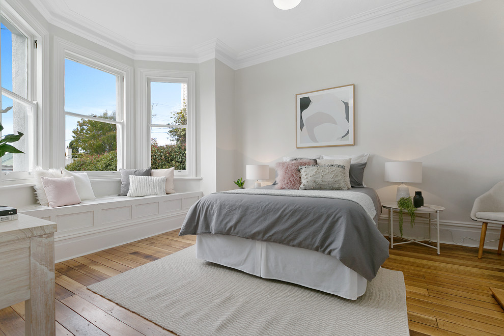 Immagine di una camera da letto minimal con pareti beige e pavimento in legno massello medio