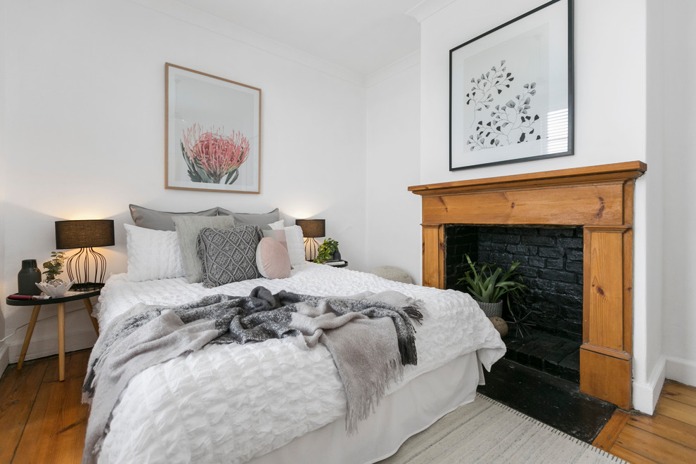 Modernes Schlafzimmer mit weißer Wandfarbe, braunem Holzboden, Kamin und Kaminumrandung aus Holz in Hobart