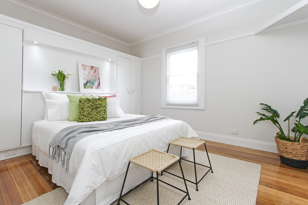 Imagen de habitación de invitados contemporánea grande con paredes grises y suelo de madera en tonos medios