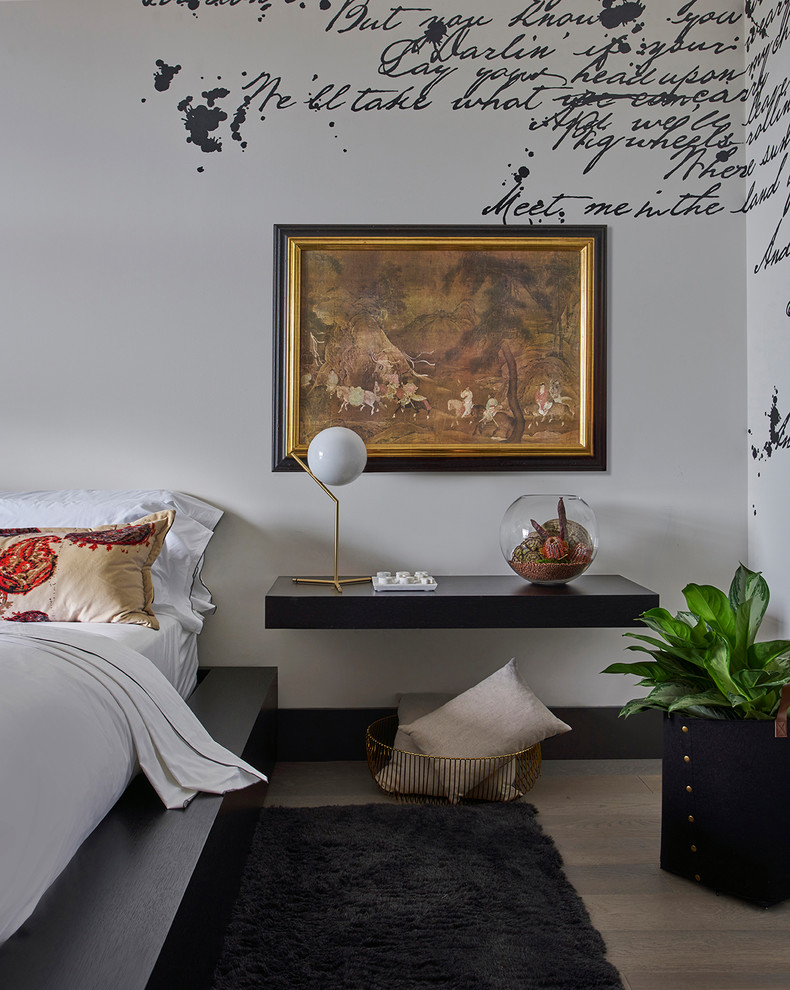 Immagine di una camera da letto design con pareti bianche, parquet chiaro e pavimento marrone