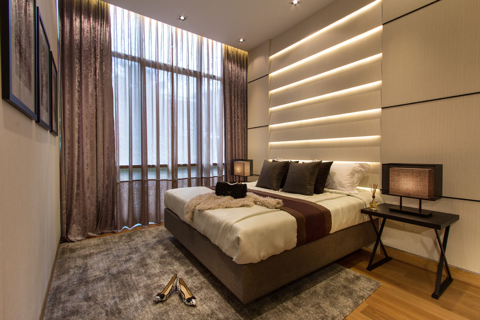 Design ideas for a contemporary master and grey and brown bedroom in Singapore with beige walls and medium hardwood flooring.