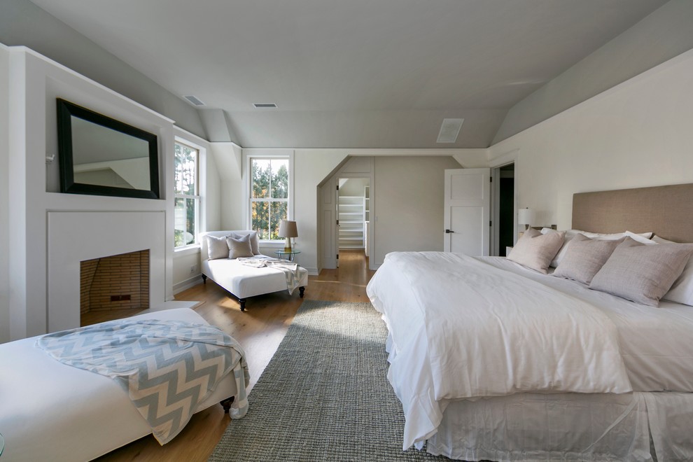 Example of a large trendy master light wood floor bedroom design in New York with white walls, a standard fireplace and a plaster fireplace