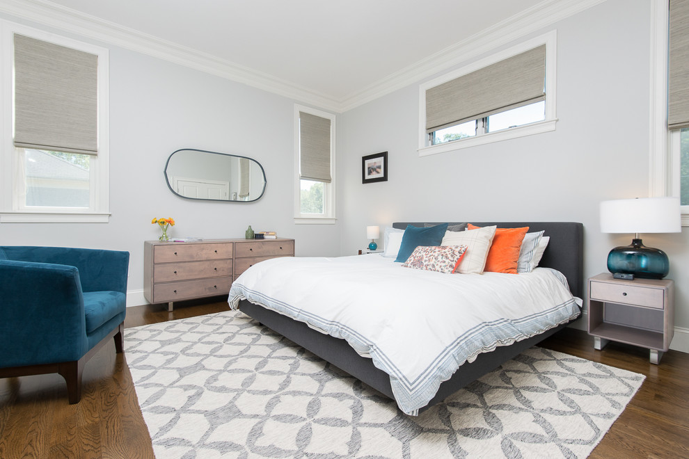 Modelo de dormitorio principal romántico grande con paredes grises y suelo de madera en tonos medios