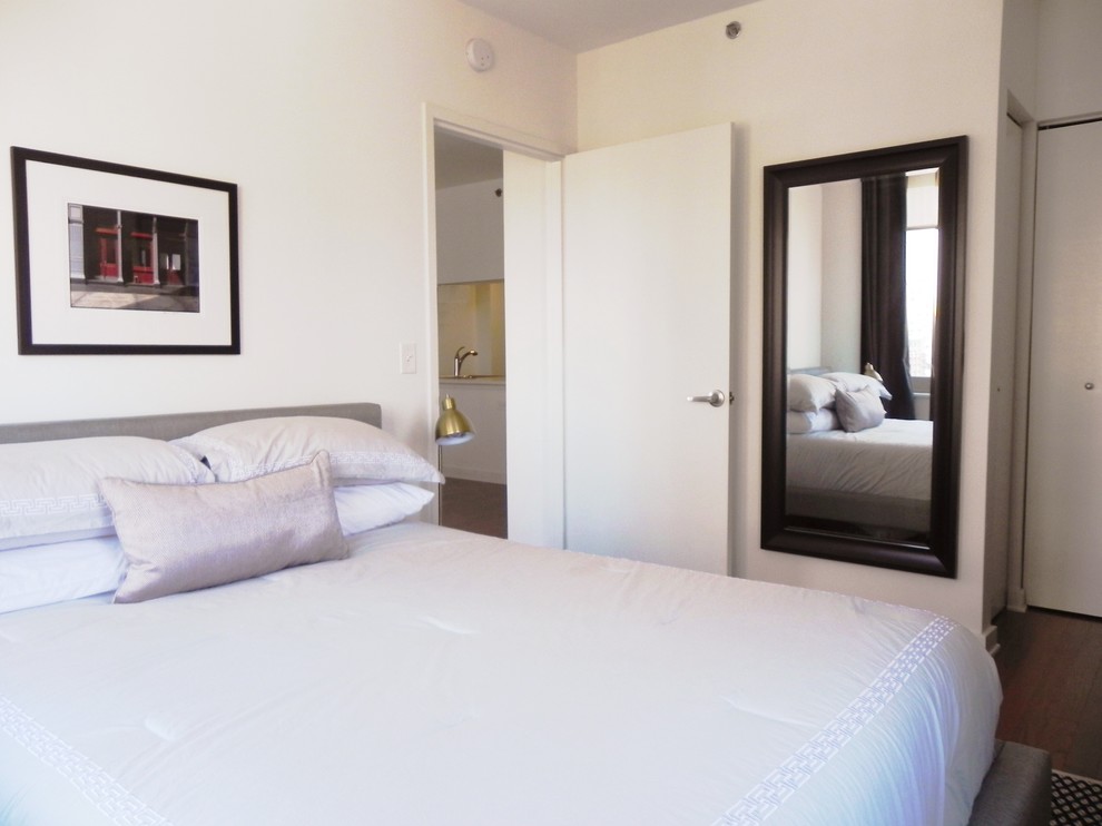 Kleines Modernes Hauptschlafzimmer ohne Kamin mit weißer Wandfarbe, braunem Holzboden und braunem Boden in New York
