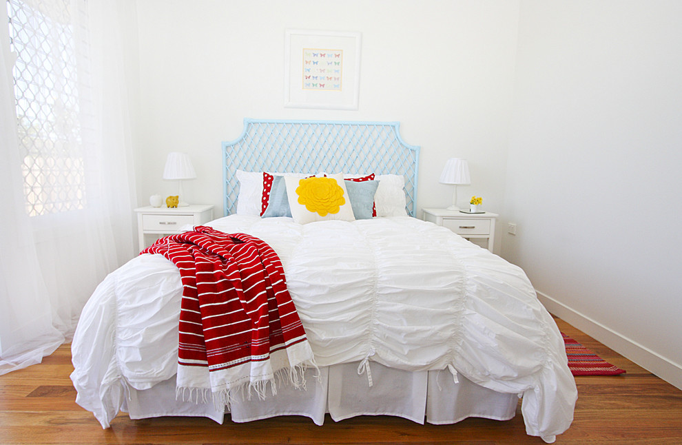 Foto de dormitorio costero de tamaño medio con paredes blancas y suelo de madera en tonos medios