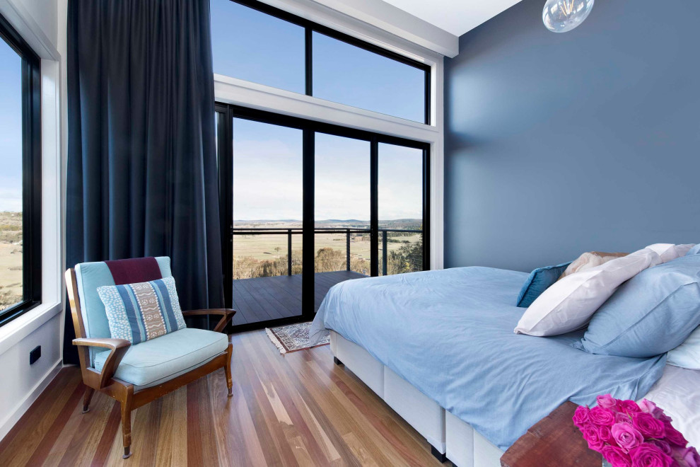 キャンベラにある小さなコンテンポラリースタイルのおしゃれな主寝室 (青い壁、無垢フローリング、暖炉なし、茶色い床) のレイアウト