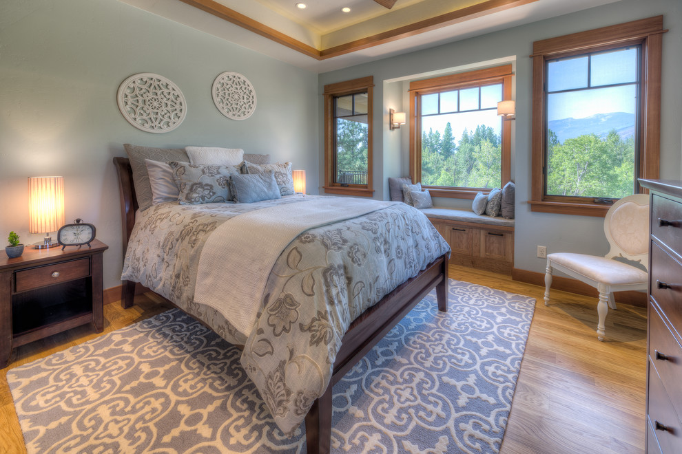 Modelo de dormitorio principal de estilo americano grande sin chimenea con paredes azules y suelo de madera en tonos medios