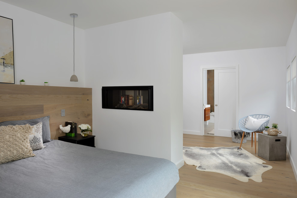 Réalisation d'une chambre parentale design de taille moyenne avec un mur blanc, parquet clair, une cheminée double-face, un manteau de cheminée en plâtre et un sol beige.