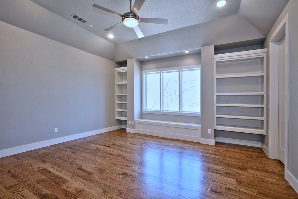 Ejemplo de habitación de invitados actual grande sin chimenea con paredes grises y suelo de madera en tonos medios