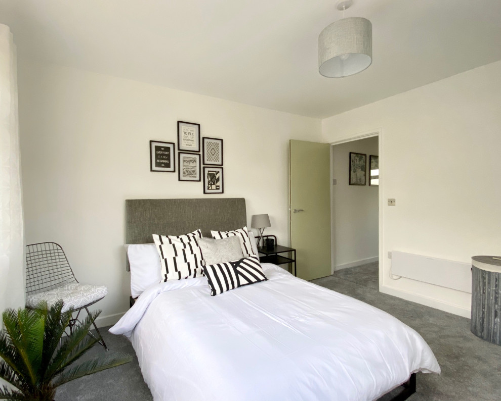 This is an example of a small contemporary master bedroom in Gloucestershire with white walls, carpet and grey floors.