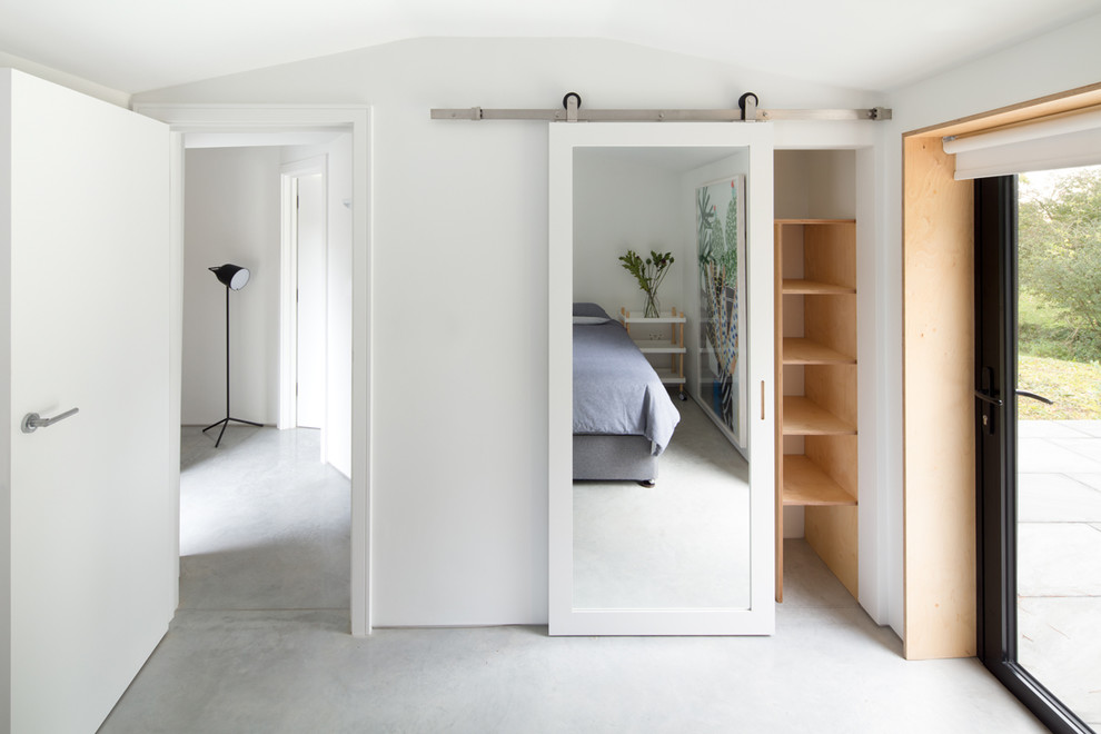Ejemplo de habitación de invitados contemporánea de tamaño medio con paredes blancas, suelo de cemento y suelo gris