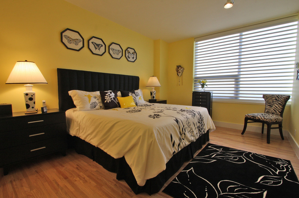 Cette image montre une chambre design avec un mur jaune, un sol en bois brun et aucune cheminée.
