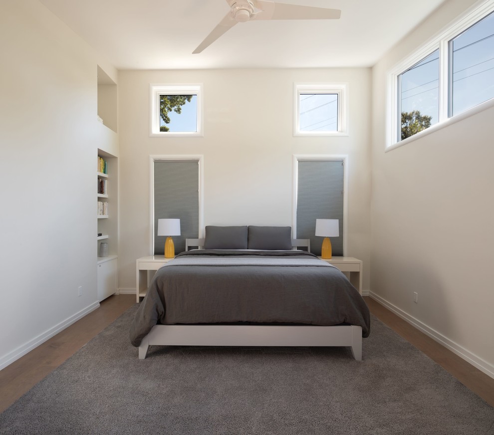 Ispirazione per una camera matrimoniale minimal con pareti beige, pavimento in legno massello medio e pavimento marrone
