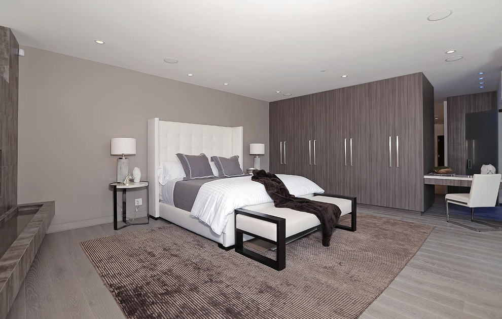 Imagen de dormitorio principal contemporáneo grande con paredes grises y suelo de madera clara