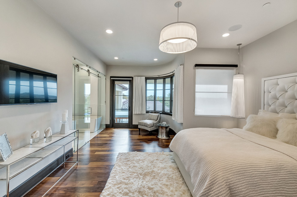 Réalisation d'une chambre parentale design avec un mur gris, parquet foncé et un sol marron.