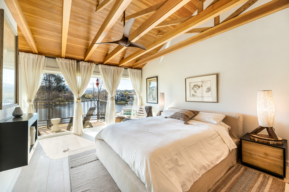 Modelo de dormitorio principal actual grande con paredes blancas, suelo de madera clara y suelo beige