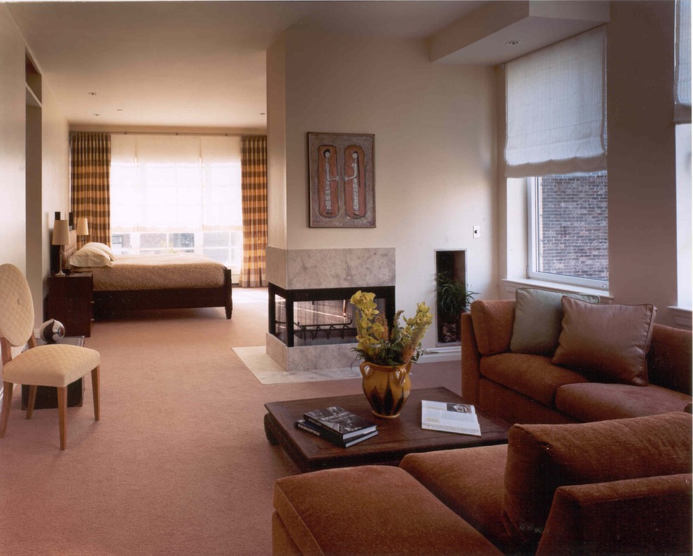 Large trendy master carpeted bedroom photo in New York with beige walls, a two-sided fireplace and a tile fireplace