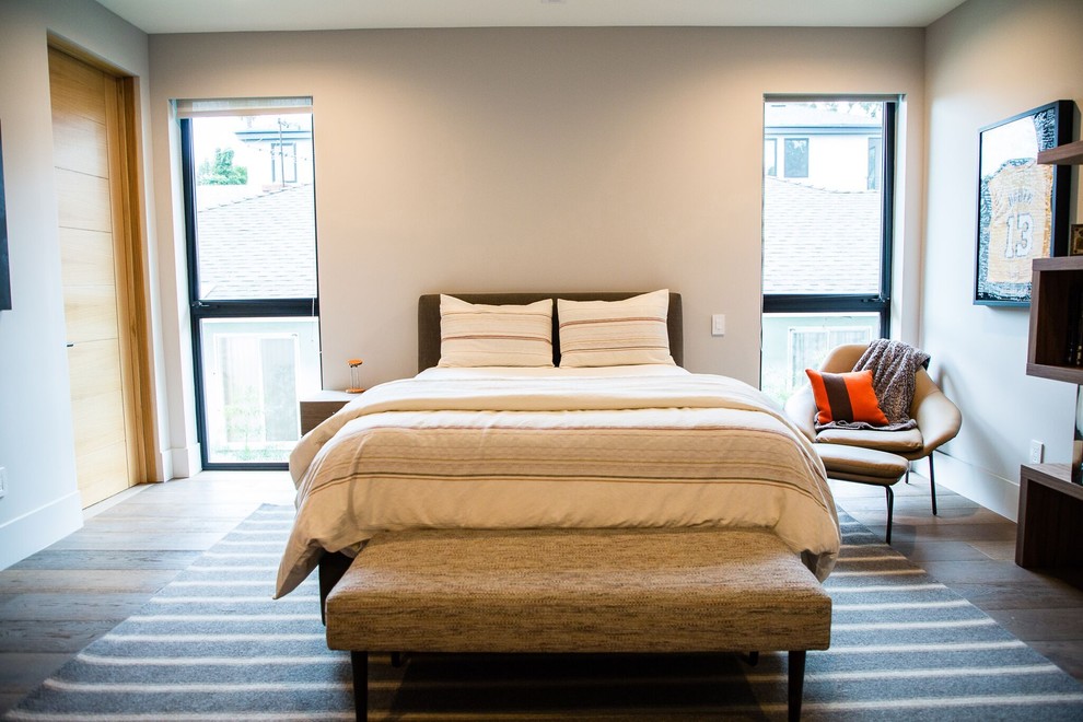 Large contemporary bedroom in Los Angeles with beige walls, medium hardwood flooring and brown floors.