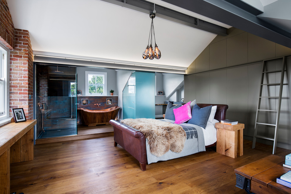 Imagen de dormitorio principal industrial grande con suelo de madera en tonos medios