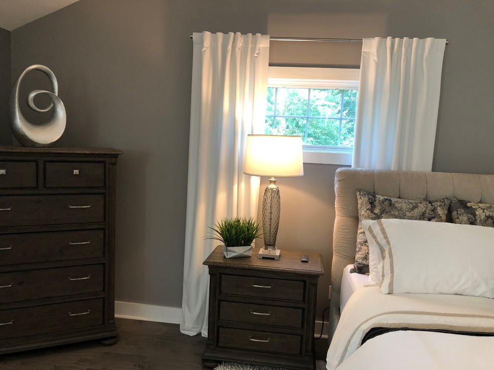 Example of a large trendy master medium tone wood floor and brown floor bedroom design in Boston with gray walls, a ribbon fireplace and a plaster fireplace