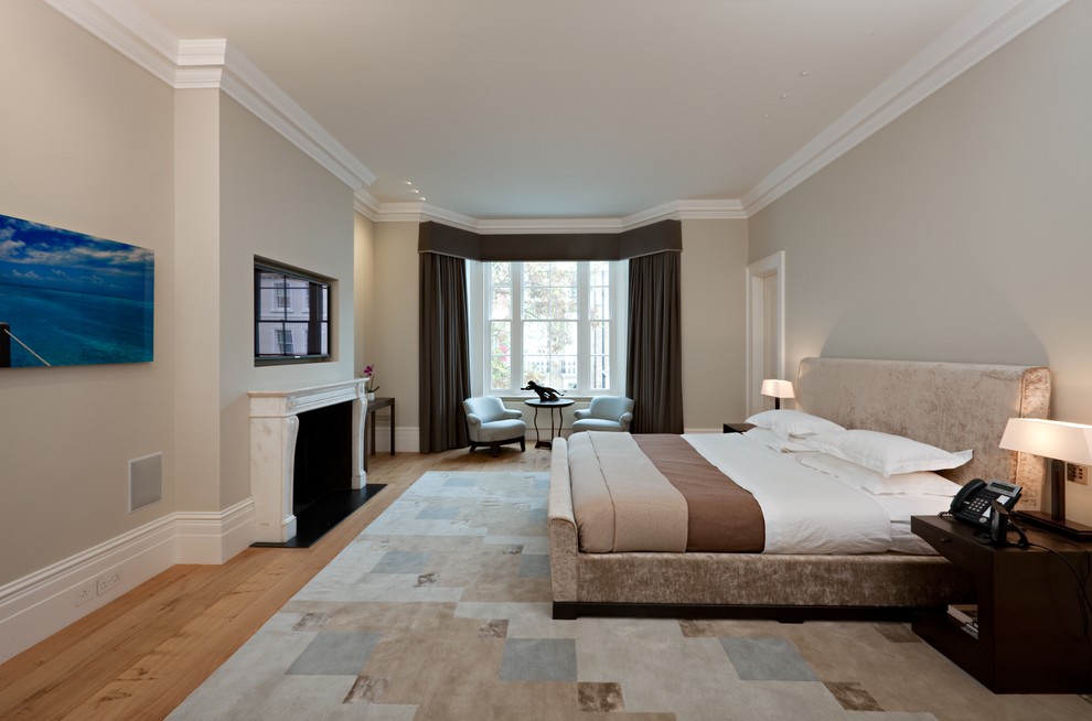 Modernes Schlafzimmer mit beiger Wandfarbe, braunem Holzboden und Kamin in London