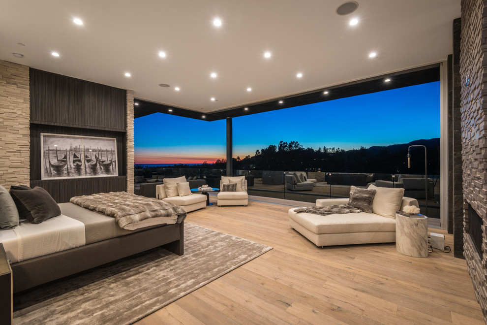 ロサンゼルスにある巨大なコンテンポラリースタイルのおしゃれな主寝室 (茶色い壁、淡色無垢フローリング、石材の暖炉まわり、横長型暖炉、ベージュの床)