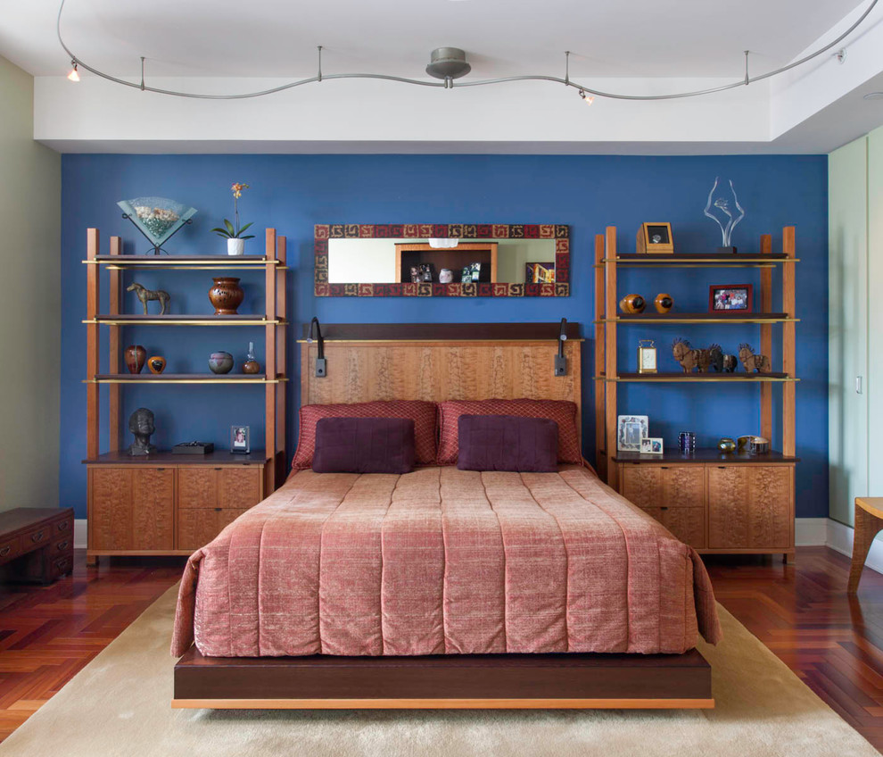 Immagine di una camera matrimoniale eclettica con pareti blu e pavimento in legno massello medio