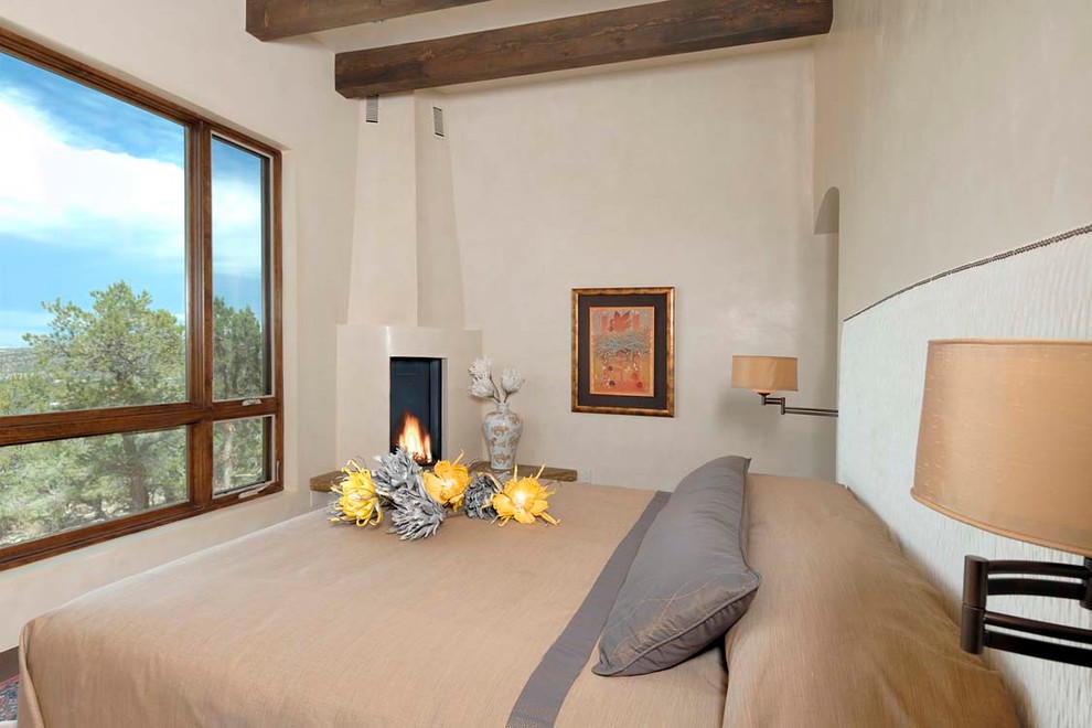 Mid-sized southwest guest bedroom photo in Albuquerque with beige walls, a corner fireplace and a plaster fireplace