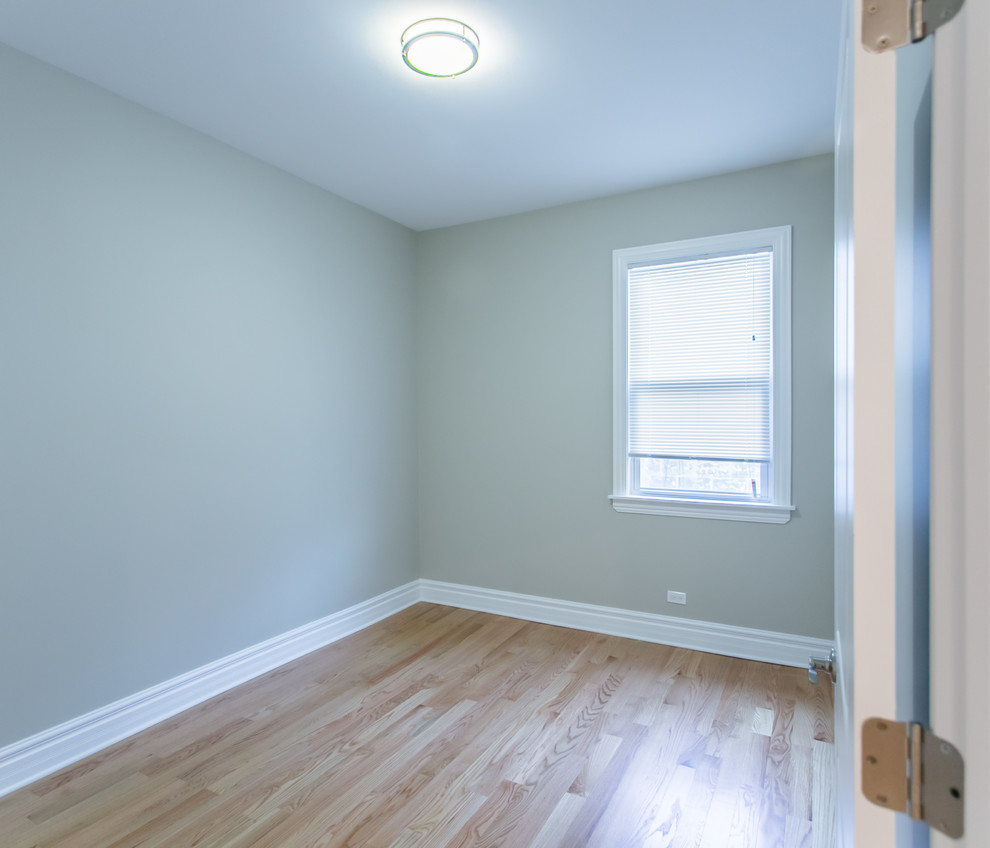 Cette photo montre une chambre tendance de taille moyenne avec un mur beige, un sol en bois brun et aucune cheminée.
