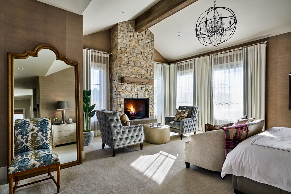 Photo of a large country master bedroom in Portland with beige walls, carpet, a standard fireplace, a stone fireplace surround and beige floors.