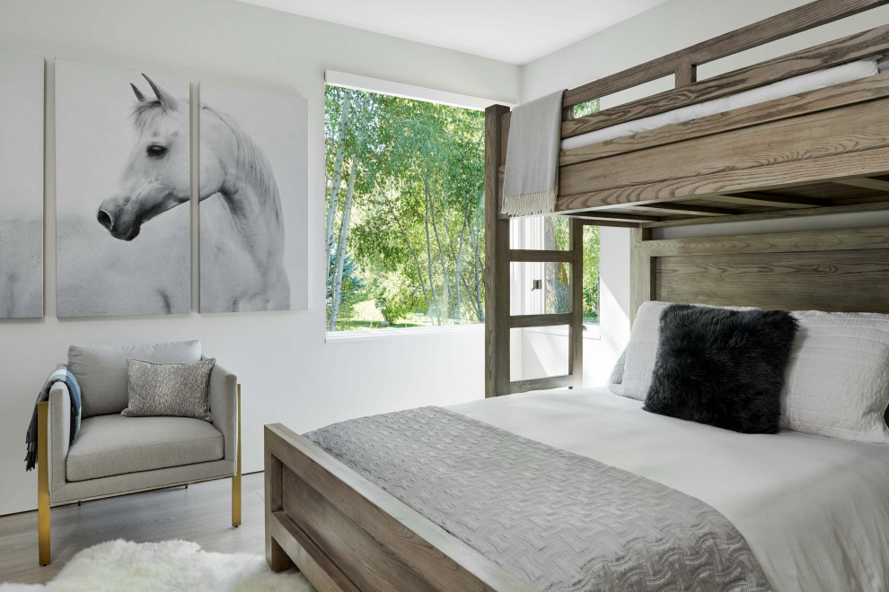 Ejemplo de habitación de invitados minimalista de tamaño medio con paredes blancas, suelo de madera clara y suelo marrón