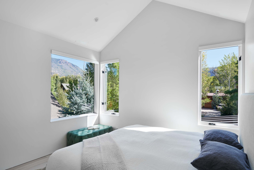 Diseño de habitación de invitados moderna de tamaño medio con paredes blancas, suelo de madera clara y suelo marrón