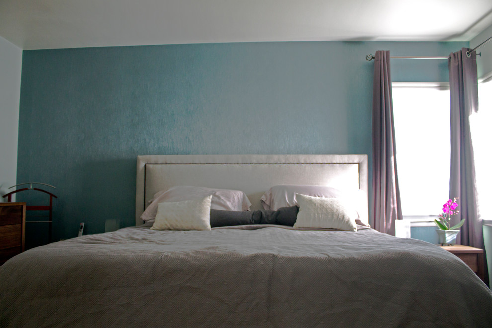 Cette photo montre une chambre parentale tendance de taille moyenne avec un sol en bois brun et un mur bleu.