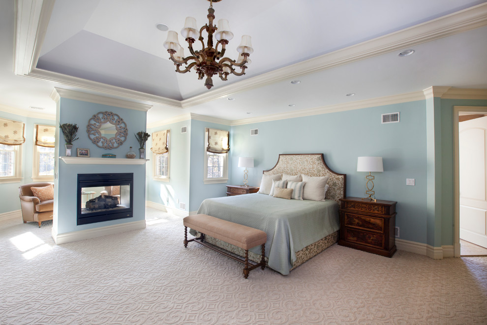 Inspiration pour une grande chambre traditionnelle avec un mur bleu, une cheminée double-face et un sol beige.