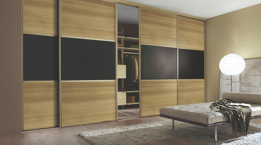 This is an example of a large contemporary master bedroom in Hampshire with beige walls and dark hardwood flooring.