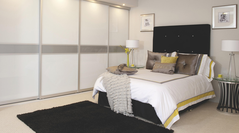 This is an example of a large contemporary master bedroom in Hampshire with white walls and carpet.