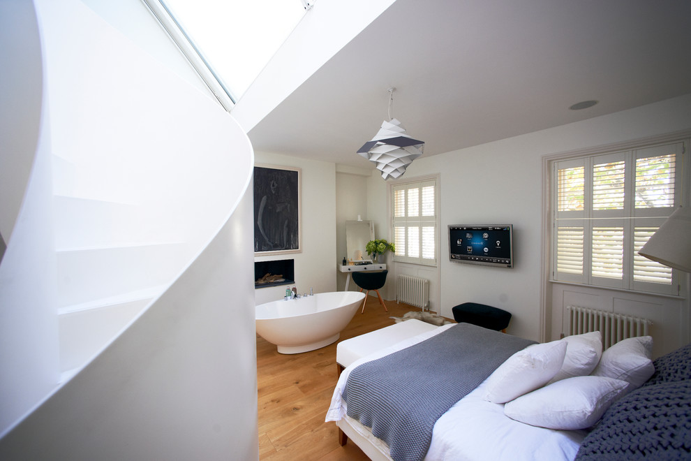 Diseño de dormitorio televisión contemporáneo con paredes blancas y suelo de madera clara