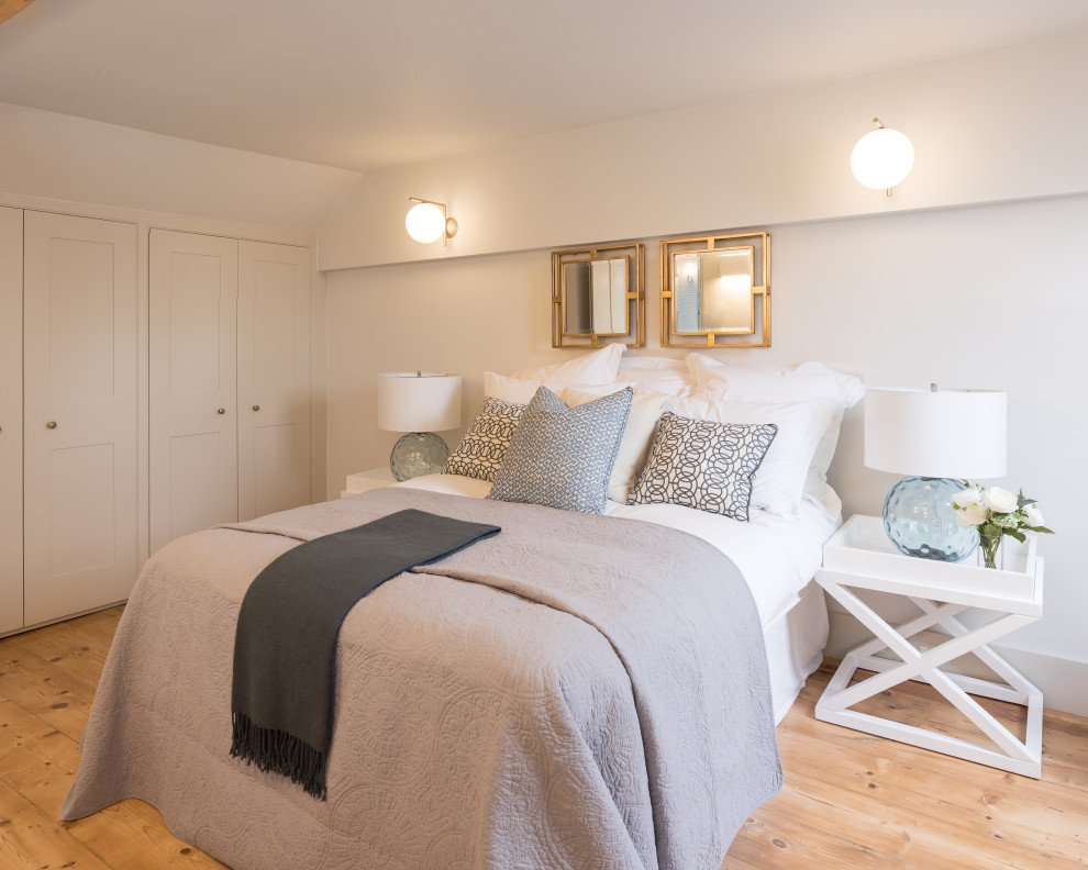 This is an example of a traditional bedroom in London with white walls, light hardwood flooring and beige floors.