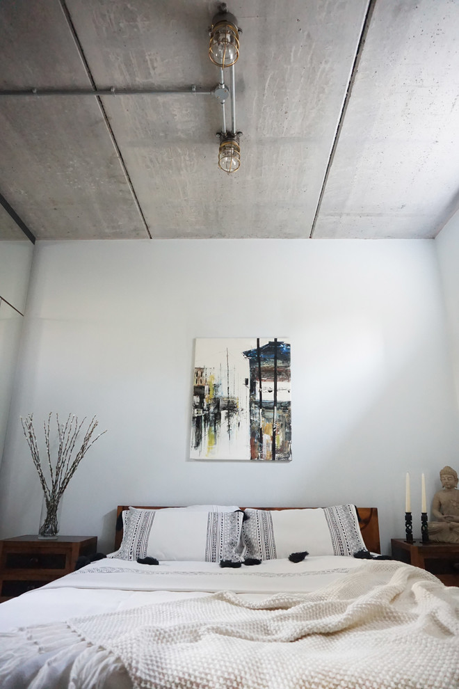 Ejemplo de dormitorio principal industrial pequeño con paredes grises y suelo de cemento