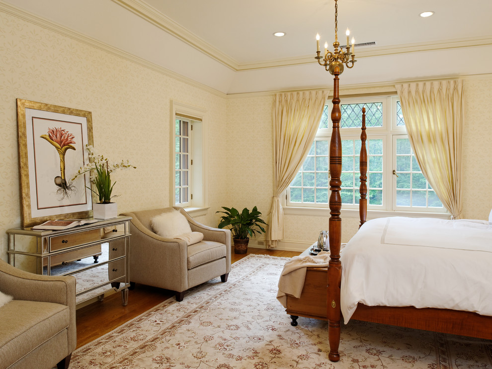 Modelo de dormitorio clásico de tamaño medio con paredes beige y suelo de madera en tonos medios