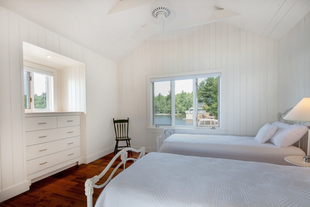 Ejemplo de habitación de invitados marinera pequeña con paredes blancas y suelo marrón
