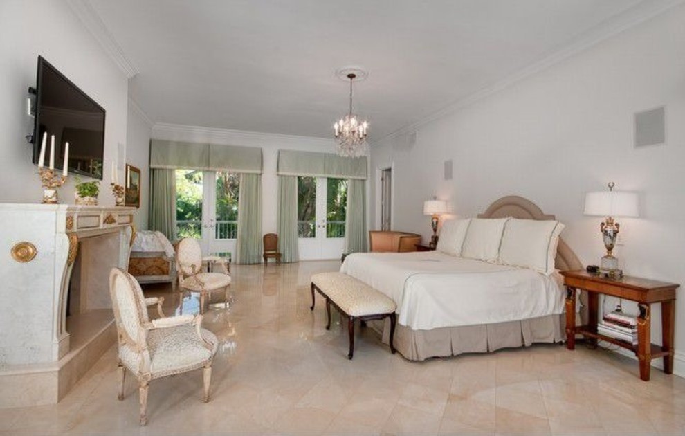 Exemple d'une grande chambre parentale tendance avec un mur blanc, un sol en marbre, une cheminée standard et un manteau de cheminée en plâtre.
