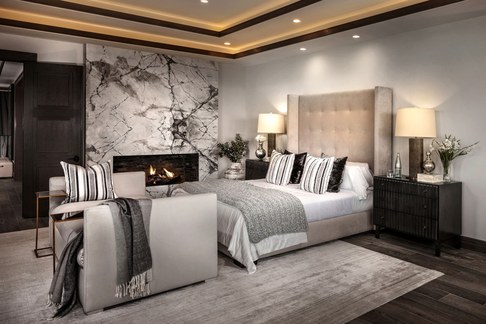 На фото: хозяйская спальня в средиземноморском стиле с белыми стенами, темным паркетным полом, горизонтальным камином и коричневым полом с
