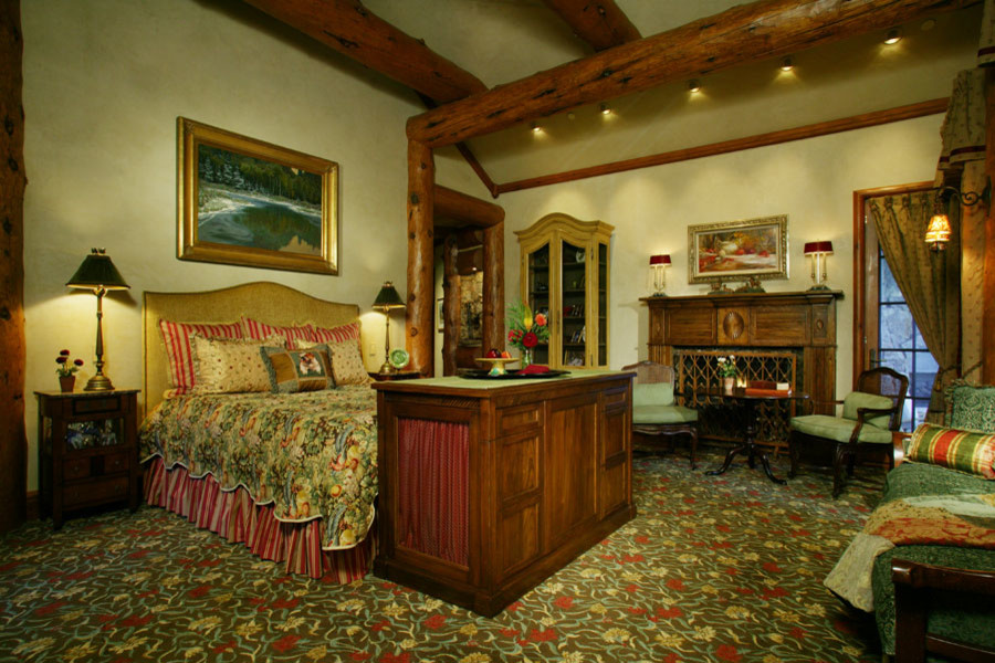 デンバーにある広いラスティックスタイルのおしゃれな主寝室 (ベージュの壁、カーペット敷き、標準型暖炉、木材の暖炉まわり、マルチカラーの床) のレイアウト