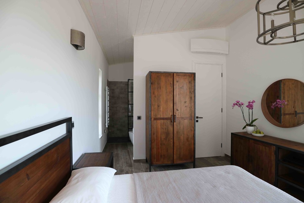 Immagine di una camera degli ospiti mediterranea con pareti bianche e pavimento marrone