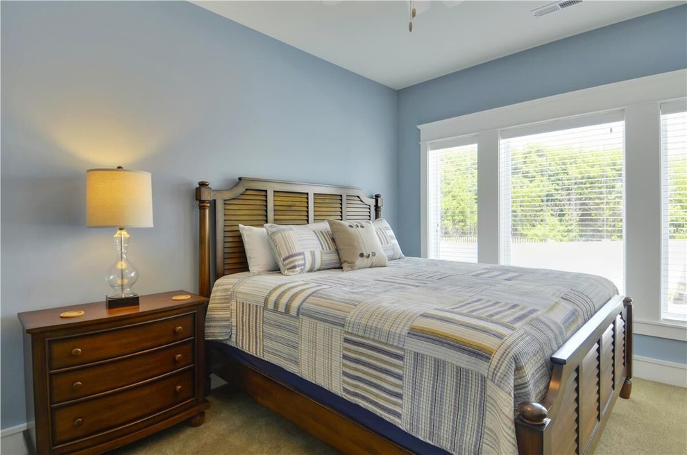 Modelo de habitación de invitados costera de tamaño medio sin chimenea con paredes azules y moqueta