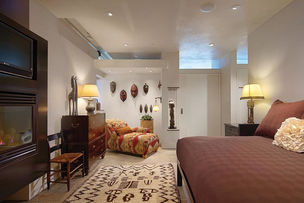 Ejemplo de habitación de invitados contemporánea de tamaño medio con paredes blancas, suelo de piedra caliza y chimenea lineal