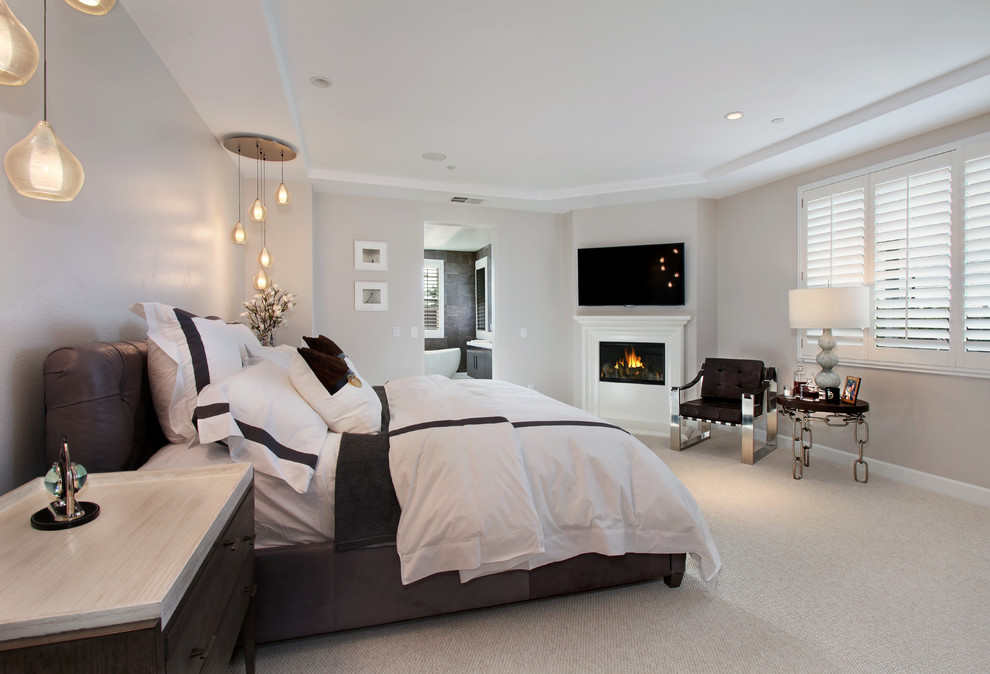 Mid-sized minimalist master carpeted bedroom photo in Los Angeles with beige walls, a corner fireplace and a wood fireplace surround